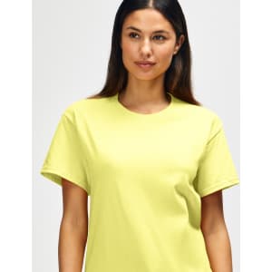 A close-up of a man wearing a bright yellow Gildan Heavy Cotton Adult T-Shirt. The shirt has a logo on it.