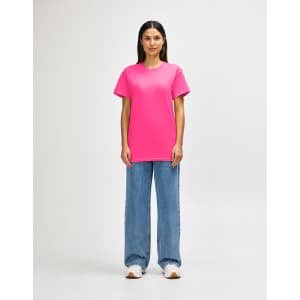 A model wearing a bright pink Gildan Heavy Cotton adult T-shirt paired with black pants and sneakers.