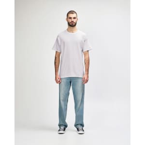 A man wearing a light grey Gildan Heavy Cotton Adult T-Shirt and blue jeans, standing against a plain background.