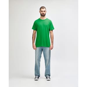 A green Gildan Heavy Cotton adult t-shirt displayed on a mannequin styled with black jeans and sneakers.