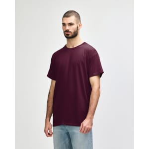 A man wearing a burgundy Gildan Heavy Cotton Adult T-Shirt, standing against a plain background.