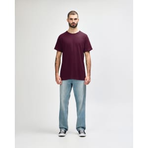 A maroon Gildan Heavy Cotton Adult T-Shirt displayed on a model wearing black jeans and sneakers.