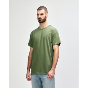A man wearing a olive green Gildan Heavy Cotton Adult T-Shirt, standing against a neutral background.