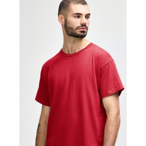 A plain red Gildan Heavy Cotton Adult T-Shirt displayed on a model, featuring a logo on the shirt.