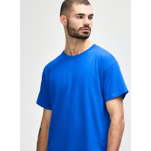 A man wearing a blue Gildan Heavy Cotton Adult T-Shirt. The shirt features a crew neckline and has a logo.