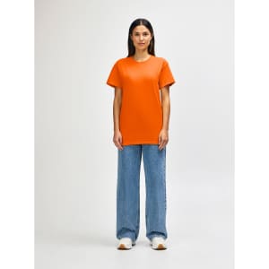 An orange Gildan Heavy Cotton adult T-shirt worn by a standing male model, paired with black jeans and sneakers.