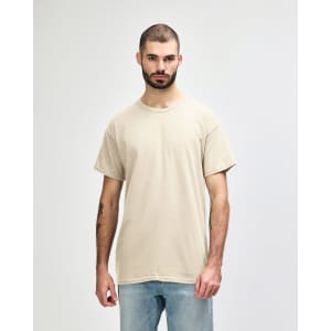 A light beige Gildan Heavy Cotton adult T-shirt worn by a male model, featuring a plain design and a logo.