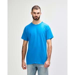 A man wears a turquoise Gildan Heavy Cotton Adult T-Shirt with short sleeves, standing against a plain background.
