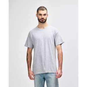 A grey T-shirt with a relaxed fit, featuring a logo on the front, displayed on a male model.