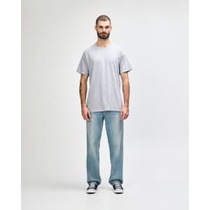 A grey Gildan Heavy Cotton adult T-shirt displayed on a male model wearing black pants and sneakers.