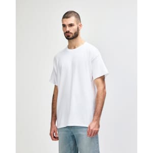 A white Gildan Heavy Cotton adult T-shirt displayed on a model with dark jeans. The shirt features a logo.