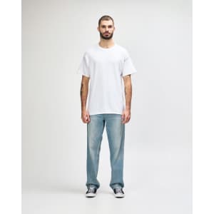 A man in a plain white Gildan Heavy Cotton T-shirt paired with blue jeans and black shoes, standing against a neutral background.