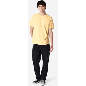A man is wearing a yellow Gildan Heavy Cotton Adult T-Shirt paired with light blue jeans and white shoes.