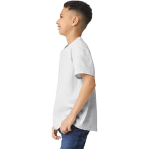 A young boy wearing a light grey Gildan Heavy Cotton Youth T-Shirt, standing sideways with a slight smile.