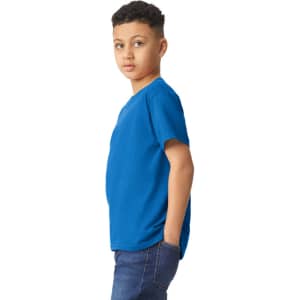 A youth T-shirt in vivid blue, featuring a branded logo, displayed on a model with hands in pockets.