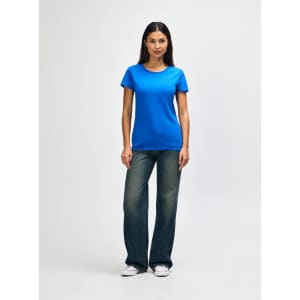 A blue Gildan Heavy Cotton Ladies' T-Shirt displayed on a model, paired with denim jeans and white sneakers.