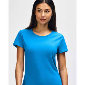 A woman smiles while wearing a bright blue Gildan Heavy Cotton ladies' t-shirt, featuring a logo on the chest.
