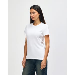 A white Gildan Heavy Cotton Ladies' T-Shirt displayed on a model, paired with blue jeans. The shirt has a simple design and a logo.