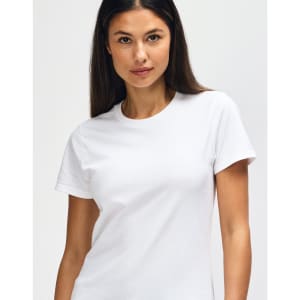 A white Gildan Heavy Cotton Ladies' T-Shirt displayed on a model, featuring a simple design and a logo.