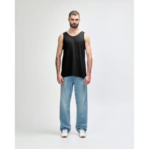 A black Gildan Heavy Cotton adult tank top worn by a model, paired with black trousers and sneakers.