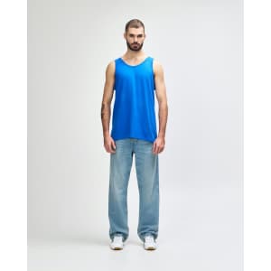 A blue tank top displayed on a model wearing black pants and sneakers, featuring a logo.