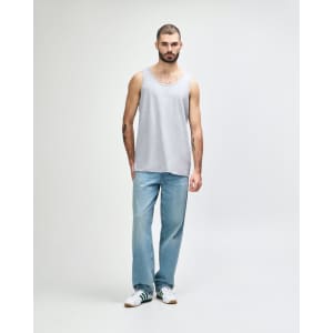 A grey Gildan Heavy Cotton adult tank top displayed on a model, paired with black pants and sneakers.