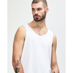 A white Gildan Heavy Cotton adult tank top on a model, showcasing the simple design and relaxed fit.