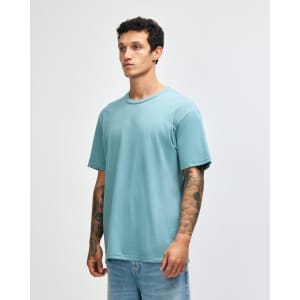 A unisex short sleeve T-shirt in a soft aqua blue colour, displayed on a model with tattoos. The shirt has a logo.