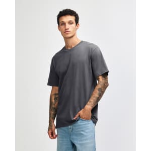 A grey sueded unisex short sleeve T-shirt displayed on a model with tattoos, featuring a brand logo.