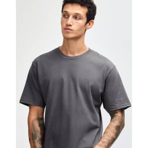 A grey short sleeve unisex T-shirt with a relaxed fit, displayed on a model with tattoos. Features a logo.
