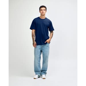 A navy blue unisex short sleeve T-shirt on a model, paired with light blue jeans. The shirt has a logo.