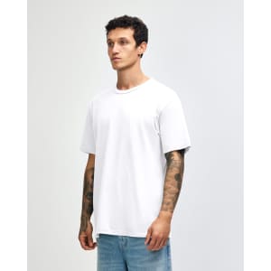 A white unisex short sleeve T-shirt displayed on a model with tattoos, featuring a simple design and relaxed fit.