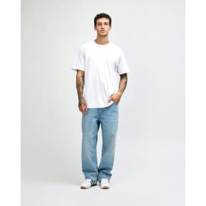 A man wearing a white sueded unisex short sleeve T-shirt and light blue jeans, standing against a neutral background.