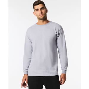 A man wearing a light grey long sleeve t-shirt with a round neck, featuring a logo on the front.