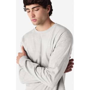 A grey long sleeve T-shirt worn by a model with arms crossed, featuring a visible logo.