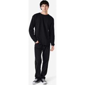 A black long sleeve t-shirt worn by a model, paired with black pants and casual shoes. The shirt has a logo.
