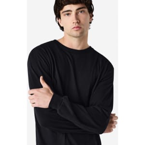 A model wearing a long sleeve t-shirt in black, featuring a logo on the sleeve.