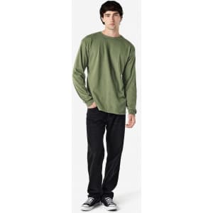 A long sleeve shirt in olive green, featuring a simple design with a logo, paired with black jeans.
