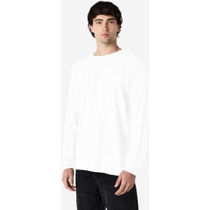 A model wearing a white long sleeve T-shirt with a simple design, paired with black jeans.