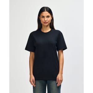 A model wearing a black Gildan Softstyle adult t-shirt paired with light blue jeans. The shirt has a logo.