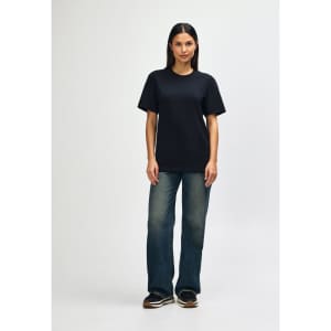 A black Gildan Softstyle adult T-shirt displayed on a model wearing light blue jeans and white shoes, with a plain background.