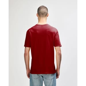 A red Gildan Softstyle adult T-shirt displayed from the back, worn by a model in denim jeans.