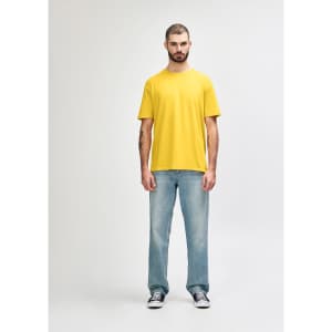A man wearing a bright yellow Gildan Softstyle adult T-shirt and grey jeans, standing casually.