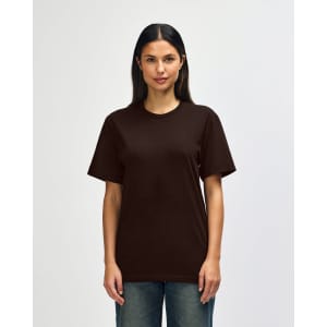 A man is wearing a brown Gildan Softstyle adult t-shirt, featuring a plain design. The shirt has a logo on it.