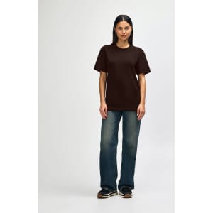 A brown Gildan Softstyle adult t-shirt displayed on a model, paired with light blue jeans and white shoes.