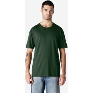 A man wearing a dark green Gildan Softstyle adult t-shirt, paired with light blue jeans. The shirt has a logo.