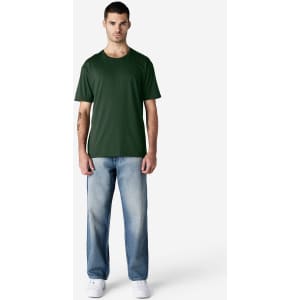 A green Gildan Softstyle adult T-shirt displayed on a model, paired with blue jeans and white shoes.