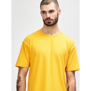 A smiling young man wearing a vibrant yellow Gildan Softstyle adult t-shirt with a logo on it.