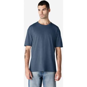 A man wearing a navy blue Gildan Softstyle adult t-shirt stands against a plain background. The shirt has a logo.