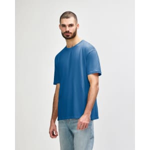 A blue Gildan Softstyle adult t-shirt is displayed on a model, featuring a simple design and relaxed fit.